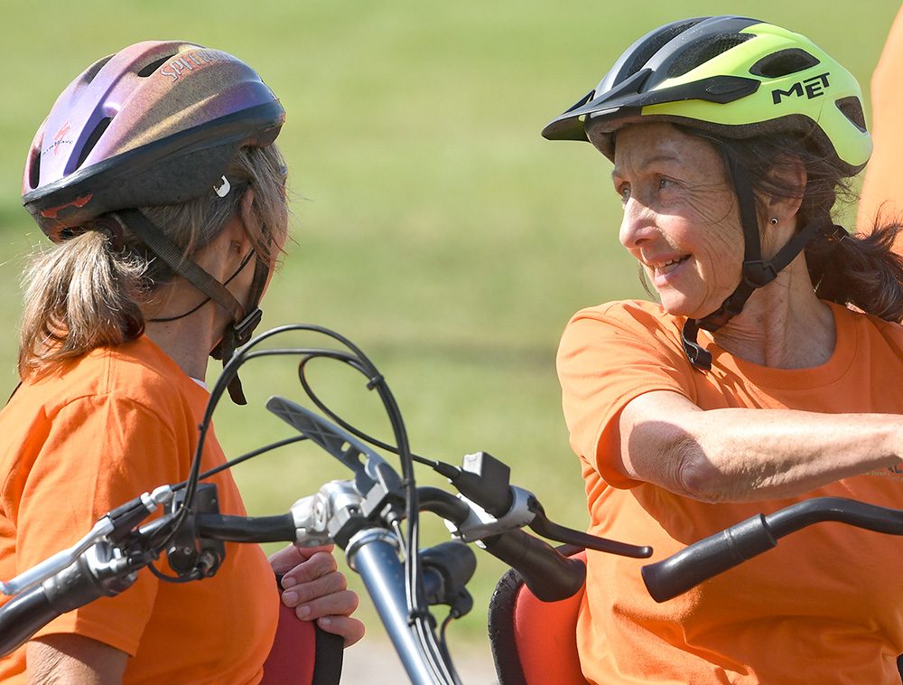 Two PEDALL volunteers on a tandem bike smiling and having a discussion